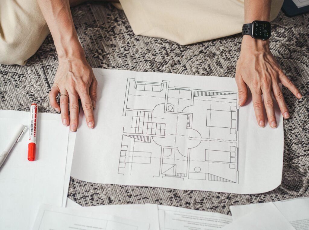 Hands on a detailed architectural floor plan paper, showcasing home design layout.