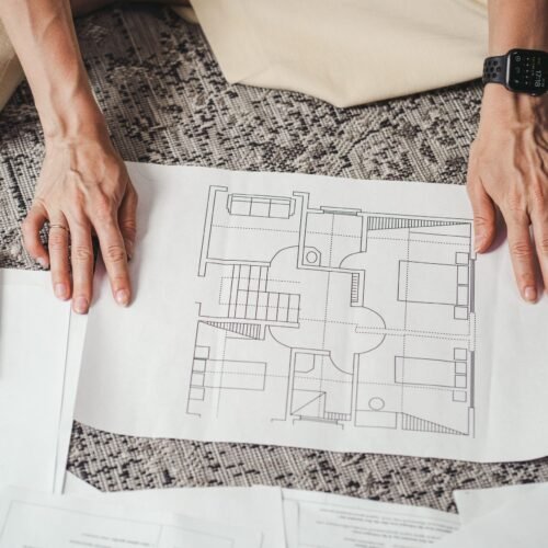 Hands on a detailed architectural floor plan paper, showcasing home design layout.