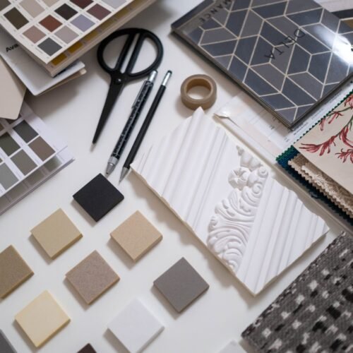 A flat lay of a designer's workspace featuring color swatches and material samples for interior design.